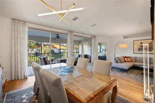 dining room with ceiling fan with notable chandelier and light hardwood / wood-style flooring