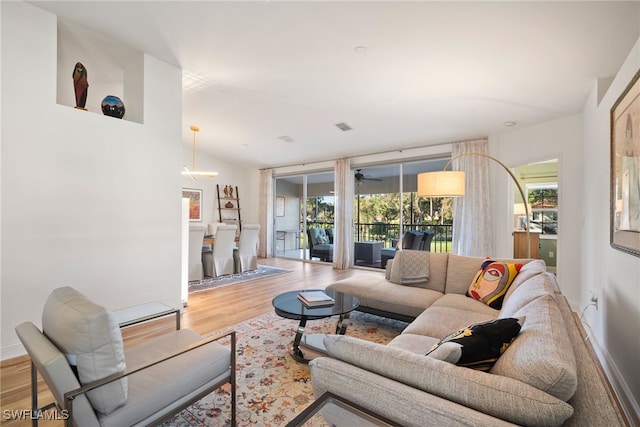 living room featuring ceiling fan, light wood-type flooring, and vaulted ceiling