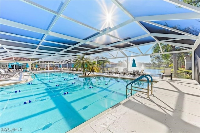 view of pool featuring a patio, a water view, and glass enclosure