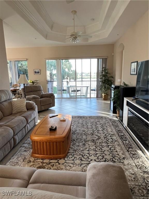 living room featuring a tray ceiling, ceiling fan, and ornamental molding