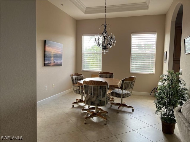 tiled dining room featuring a notable chandelier, ornamental molding, and a tray ceiling