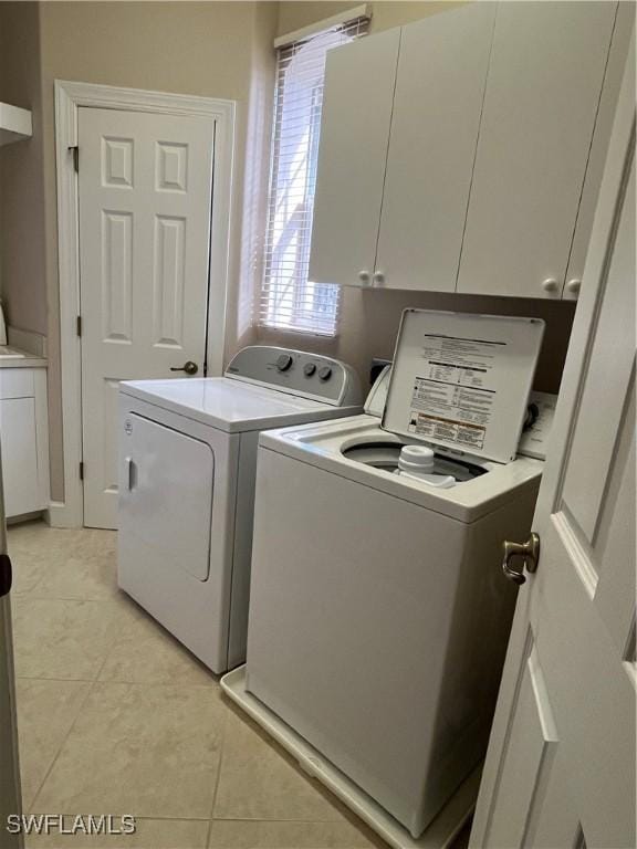 washroom with cabinets, light tile patterned floors, and washing machine and dryer