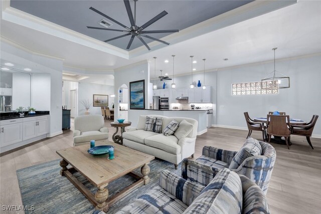 5620 Hammock Isles Dr, Naples, FL 34119 - living area featuring a chandelier, a raised ceiling, light wood-style flooring, a ceiling fan, and crown molding