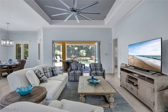 5620 Hammock Isles Dr, Naples, FL 34119 - living room with a chandelier, a raised ceiling, light wood-style floors, ceiling fan, and crown molding