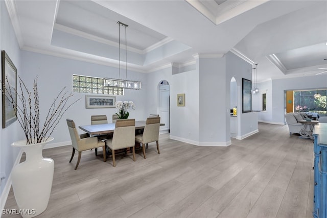 dining area featuring light wood-type flooring, a raised ceiling, and crown molding