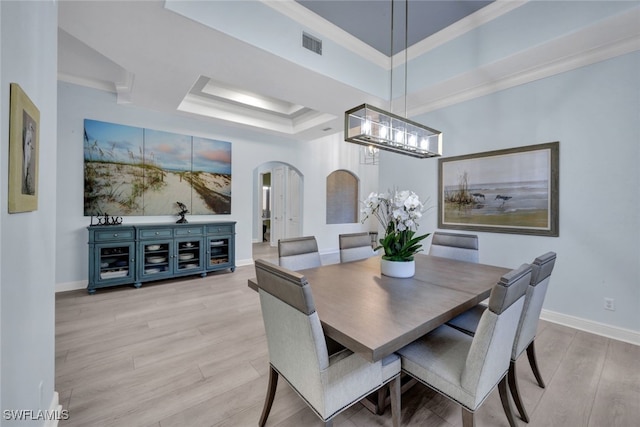 5620 Hammock Isles Dr, Naples, FL 34119 - dining space with arched walkways, a chandelier, a raised ceiling, light wood-style flooring, and ornamental molding