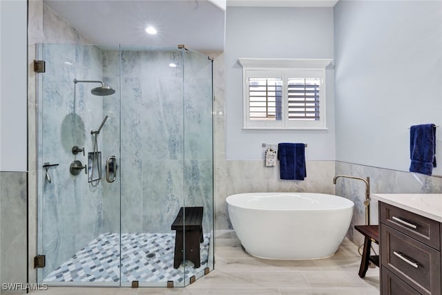 bathroom with vanity, tile walls, and shower with separate bathtub