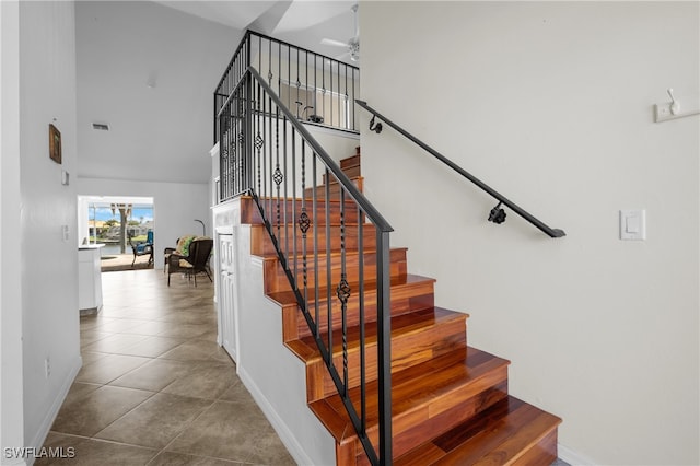 stairway featuring tile patterned floors and a towering ceiling