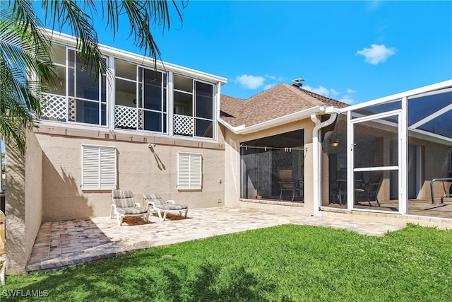 rear view of house featuring glass enclosure, a patio area, and a lawn