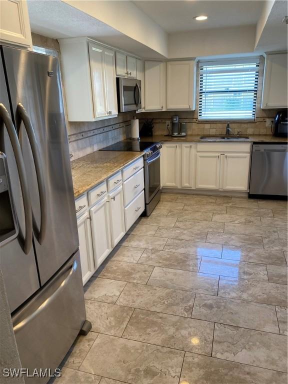 kitchen featuring white cabinets, stainless steel appliances, tasteful backsplash, and sink