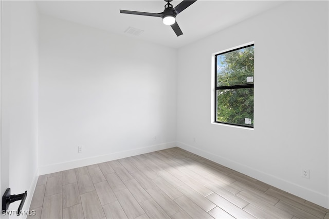 empty room featuring plenty of natural light, ceiling fan, and light wood-type flooring