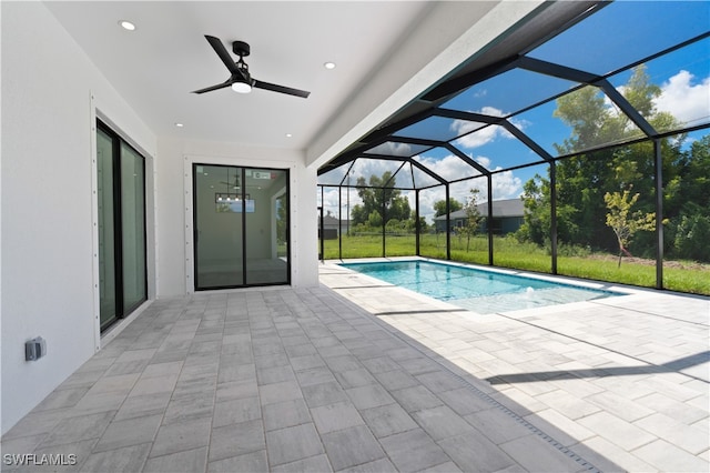 view of pool featuring glass enclosure, ceiling fan, and a patio area