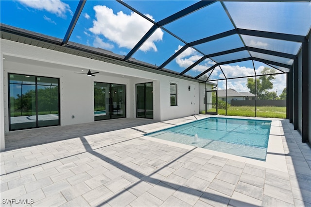 view of swimming pool with ceiling fan, a patio area, and glass enclosure