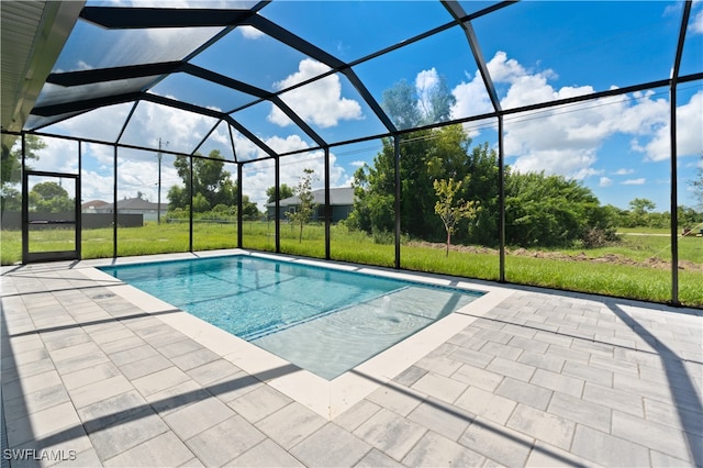 view of swimming pool with a yard, glass enclosure, and a patio area