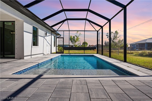 pool at dusk featuring a patio and a lanai