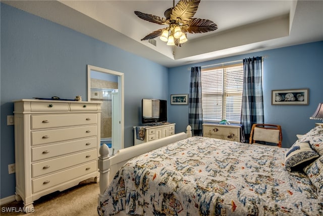 carpeted bedroom with ceiling fan and a raised ceiling