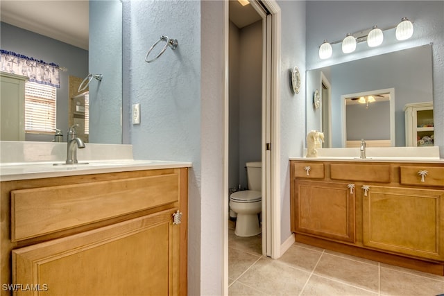 bathroom with toilet, vanity, and tile patterned floors