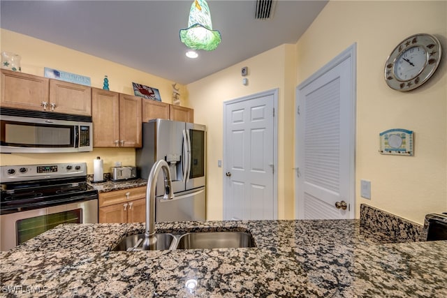 kitchen featuring decorative light fixtures, appliances with stainless steel finishes, sink, and dark stone counters