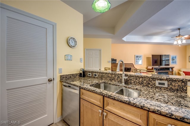 kitchen featuring stainless steel dishwasher, ceiling fan, dark stone counters, and sink