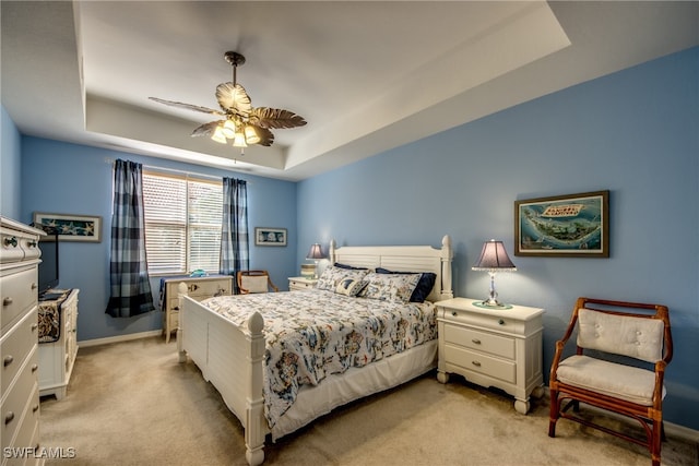 carpeted bedroom featuring ceiling fan and a raised ceiling