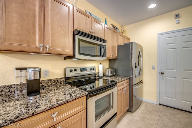 kitchen featuring light tile patterned floors, dark stone countertops, and stainless steel appliances