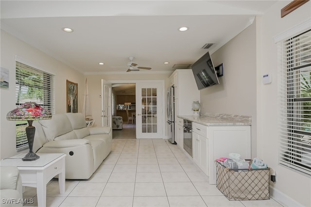 living room with ceiling fan, french doors, light tile patterned floors, and ornamental molding