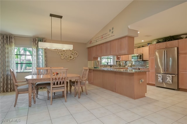 kitchen featuring kitchen peninsula, appliances with stainless steel finishes, light tile patterned floors, decorative light fixtures, and stone counters