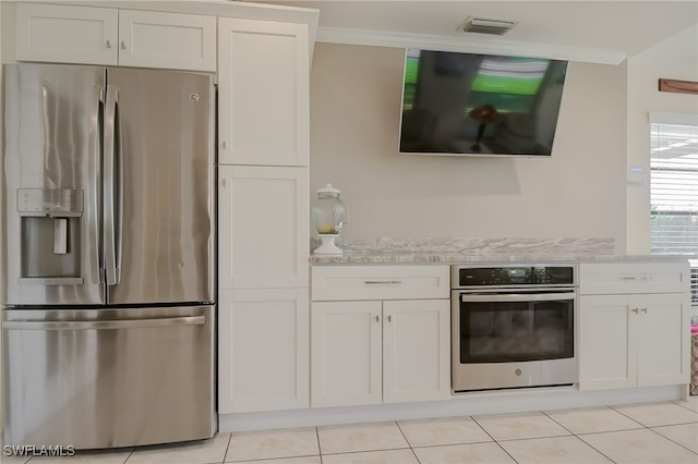 kitchen with light stone counters, white cabinets, light tile patterned flooring, and appliances with stainless steel finishes