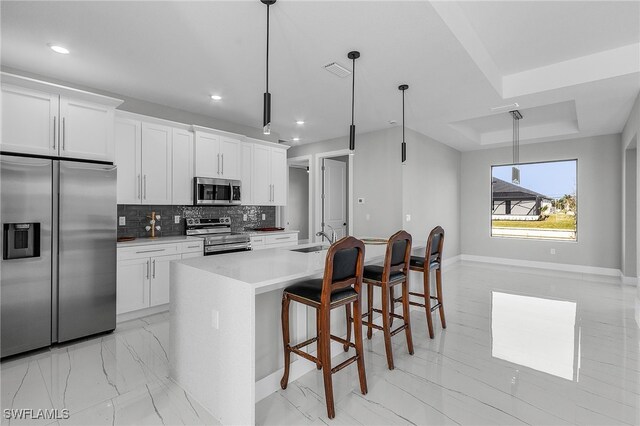 1517 SW 28th Ter, Cape Coral, FL 33914 - kitchen featuring white cabinetry, a kitchen island with sink, stainless steel appliances, pendant lighting, and decorative backsplash