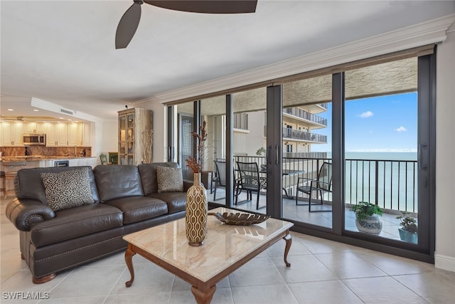 tiled living room featuring a water view, ceiling fan, and ornamental molding