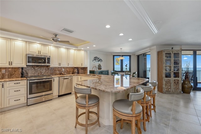 kitchen with hanging light fixtures, a breakfast bar area, decorative backsplash, light stone countertops, and stainless steel appliances