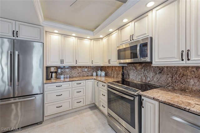 kitchen featuring white cabinets, a raised ceiling, light stone counters, and appliances with stainless steel finishes