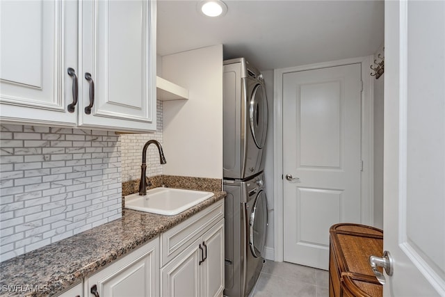 washroom featuring cabinets, stacked washer and dryer, sink, and light tile patterned floors