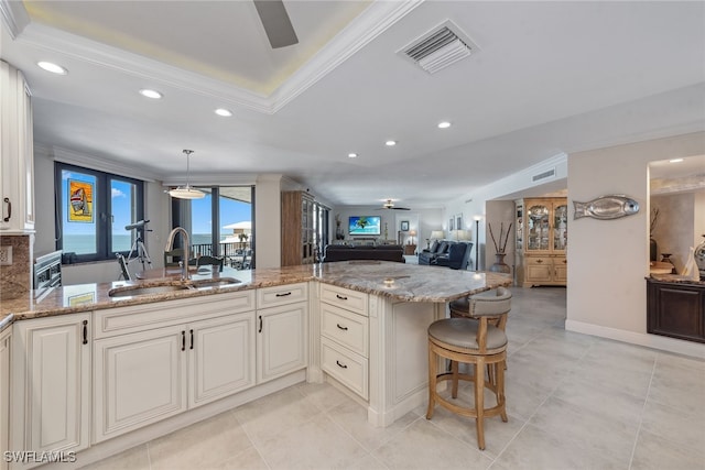 kitchen featuring pendant lighting, light stone counters, ceiling fan, and sink