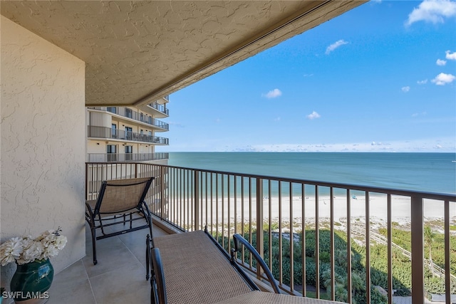 balcony featuring a view of the beach and a water view