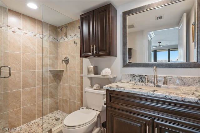 bathroom featuring ceiling fan, toilet, a shower with door, and vanity