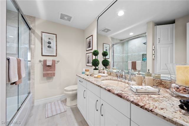 full bathroom with hardwood / wood-style flooring, vanity, toilet, and enclosed tub / shower combo