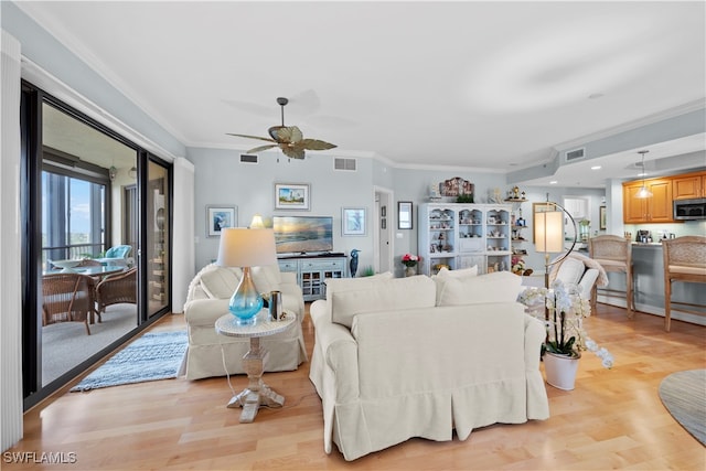 living room featuring light hardwood / wood-style floors, ceiling fan, and crown molding