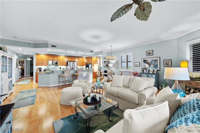 living room with light wood-type flooring, an inviting chandelier, and ornamental molding