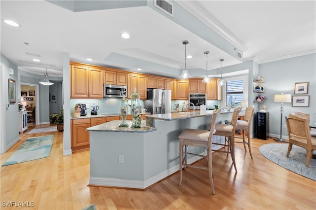 kitchen with decorative backsplash, light hardwood / wood-style floors, stainless steel appliances, and a kitchen island with sink