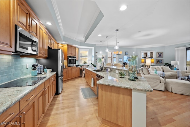 kitchen featuring appliances with stainless steel finishes, light wood-type flooring, a wealth of natural light, and a large island