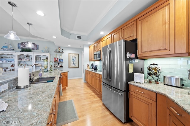 kitchen with light stone countertops, sink, stainless steel appliances, light hardwood / wood-style flooring, and backsplash