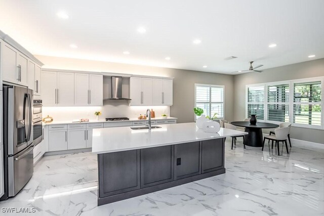 kitchen with a sink, white cabinets, light countertops, wall chimney range hood, and appliances with stainless steel finishes