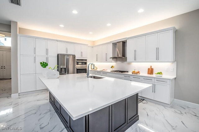 kitchen with a large island, light countertops, appliances with stainless steel finishes, a sink, and wall chimney exhaust hood