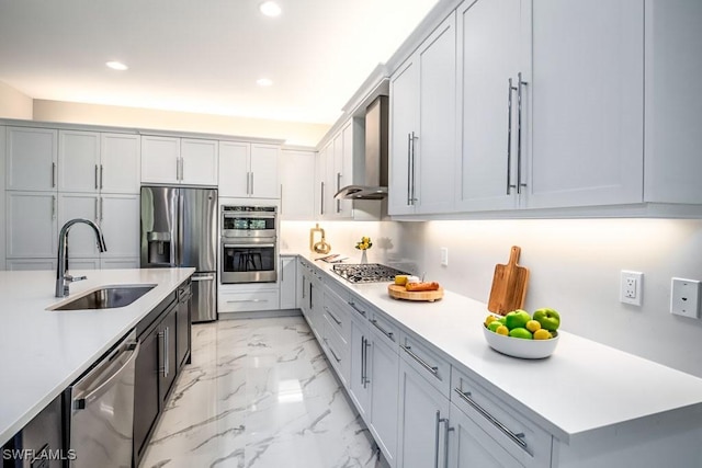 kitchen with marble finish floor, stainless steel appliances, light countertops, a sink, and wall chimney range hood