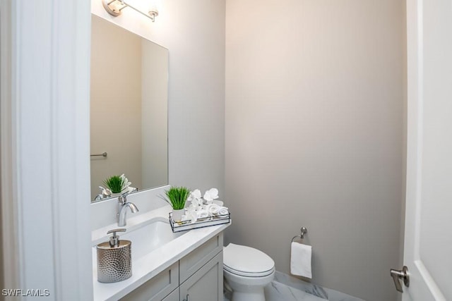 bathroom with marble finish floor, vanity, and toilet