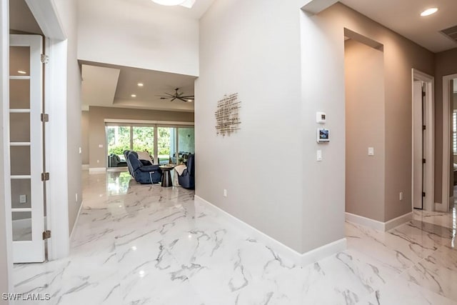 hall featuring marble finish floor, baseboards, and recessed lighting