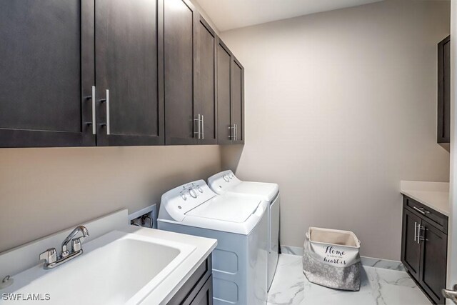 washroom with washing machine and dryer, marble finish floor, cabinet space, and a sink