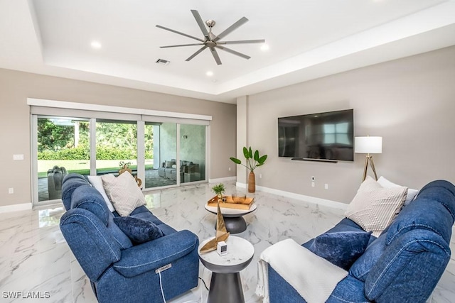 living room with marble finish floor, baseboards, visible vents, and a tray ceiling