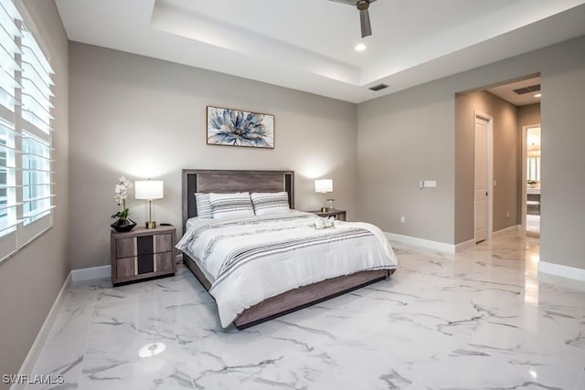 bedroom with marble finish floor, visible vents, a tray ceiling, and baseboards